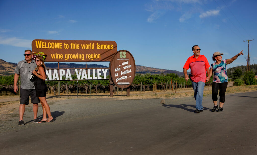 Pedestrians explore the Napa Valley Vine Trail by the iconic Welcome to Napa Valley sign.